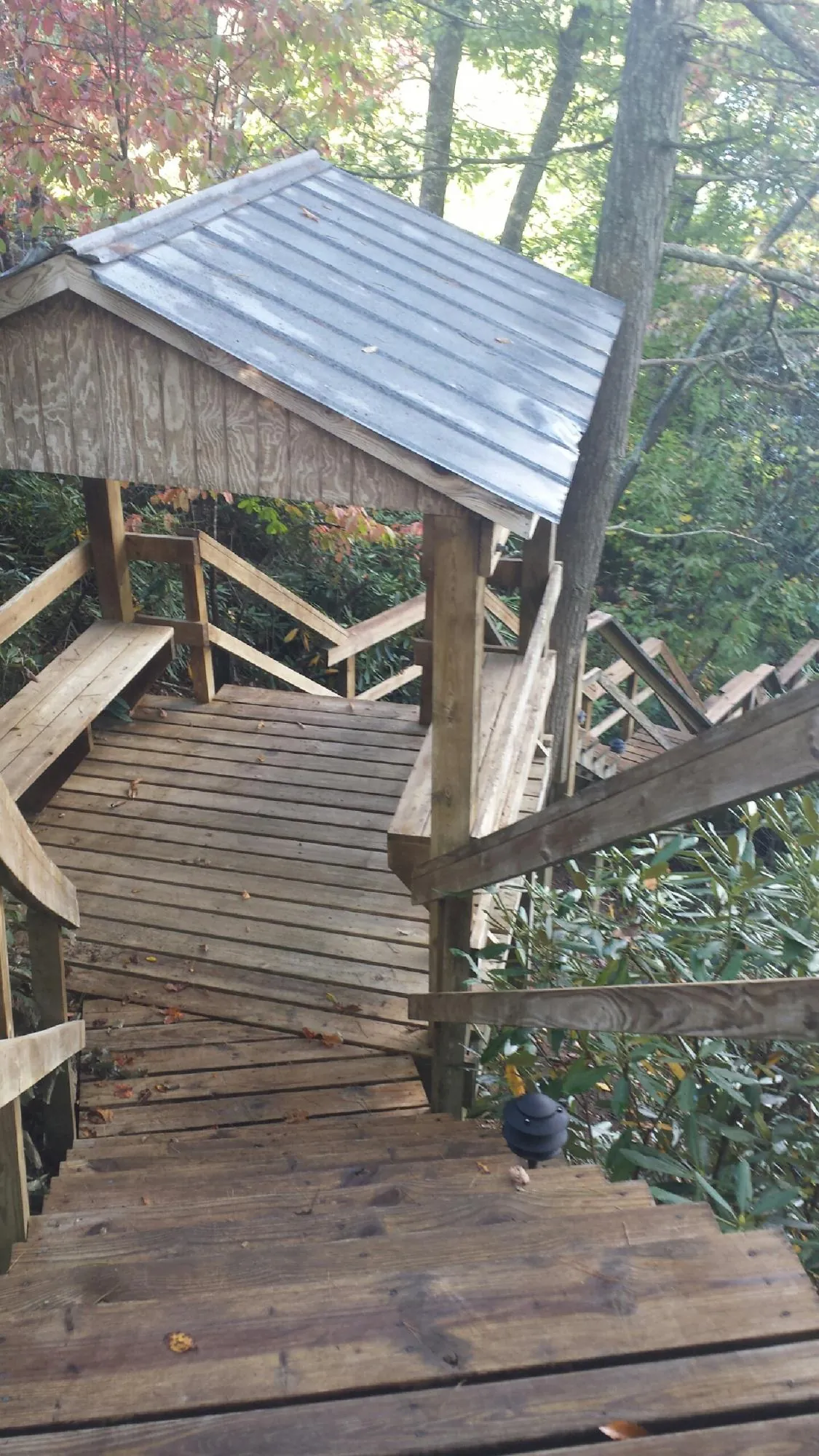 Metal roofed shelter over wooden steps on a wooded walkway — Skylight Repair & Installation work by our crew in Glenville